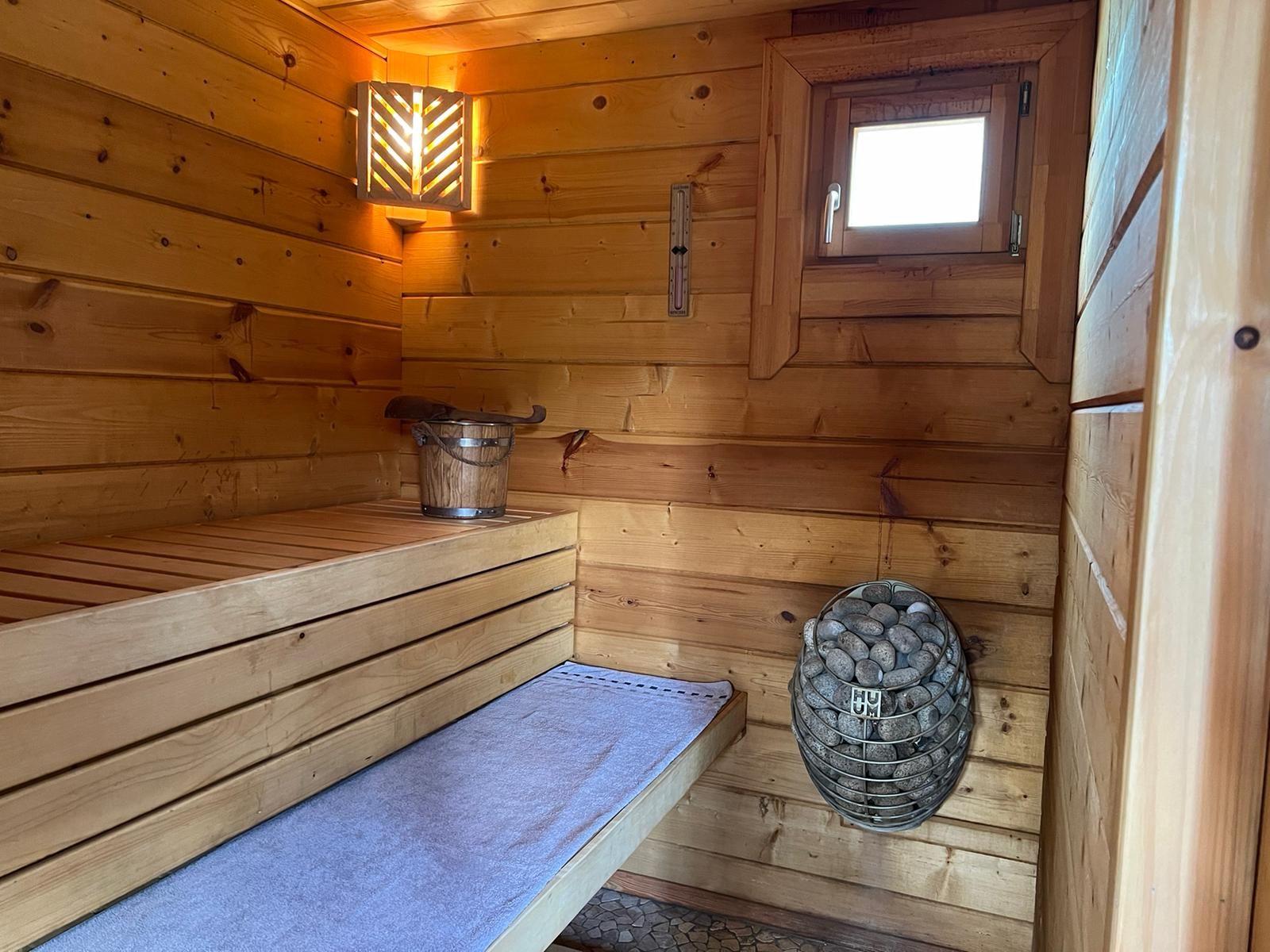 Innenraum der Sauna mit Holzbank und Saunaofen